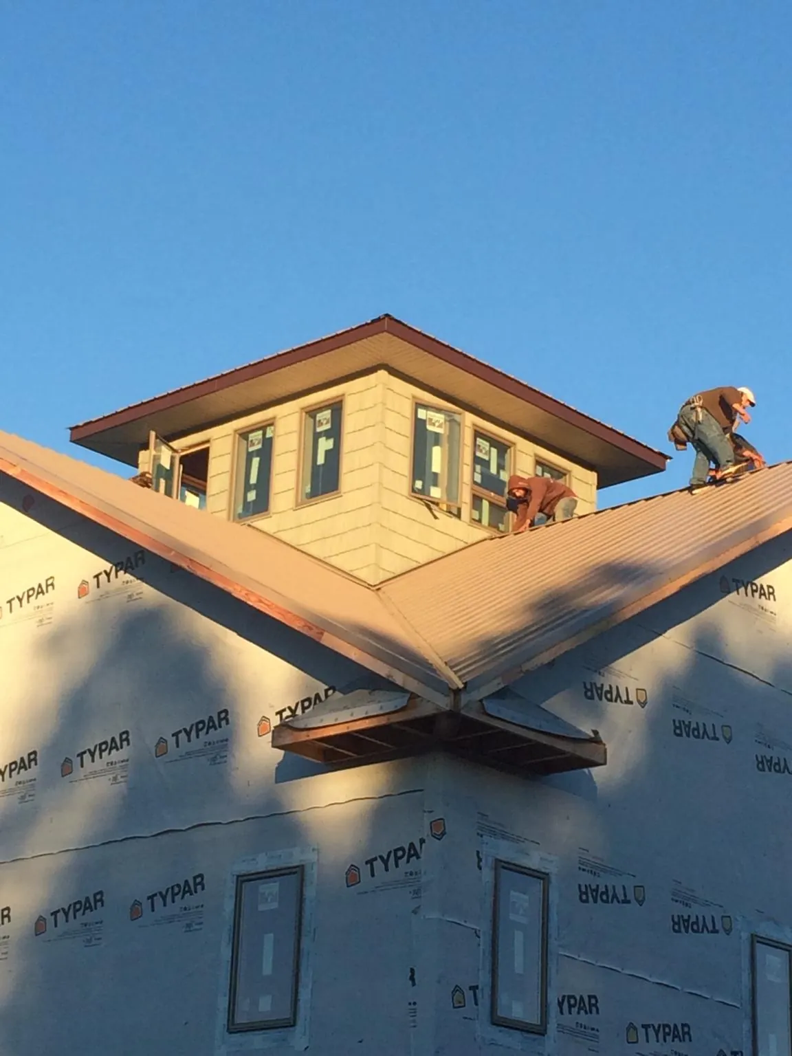 Roofers working around a rooftop cupola on a new metal roof at sunset — Roof Waterproofing in Winfield by Roofing Brothers